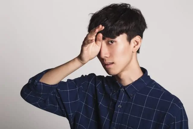 Studio portrait of a young man covering his face with one hand