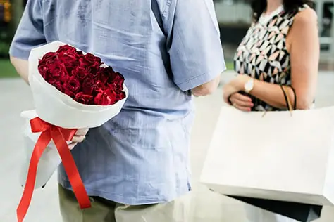 Guy hiding a bouquet of flower