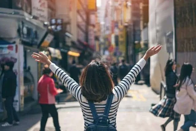 Young Asian Woman in Myeongdong holding her arms up to the sky