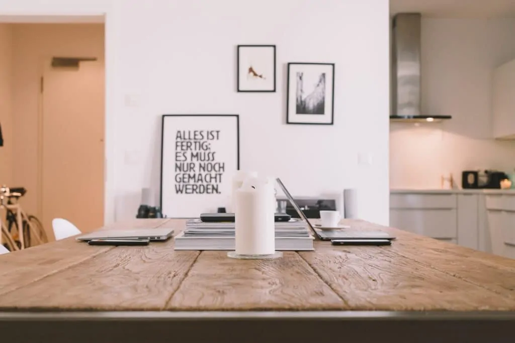 Table in an apartment with a candle and some books on it