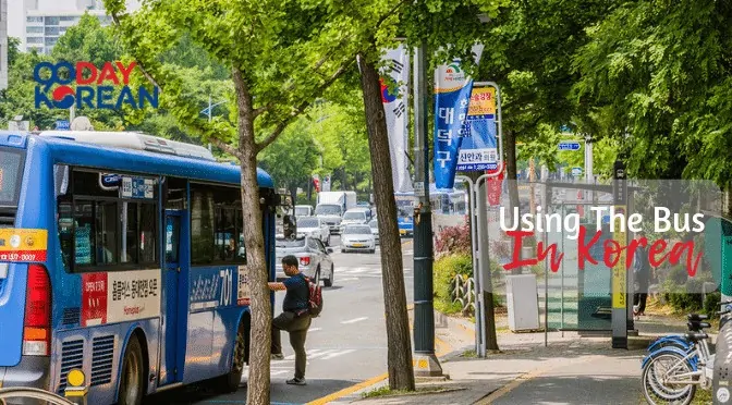 A Korean bus stop in a rural area with many trees with a person getting on to a bus