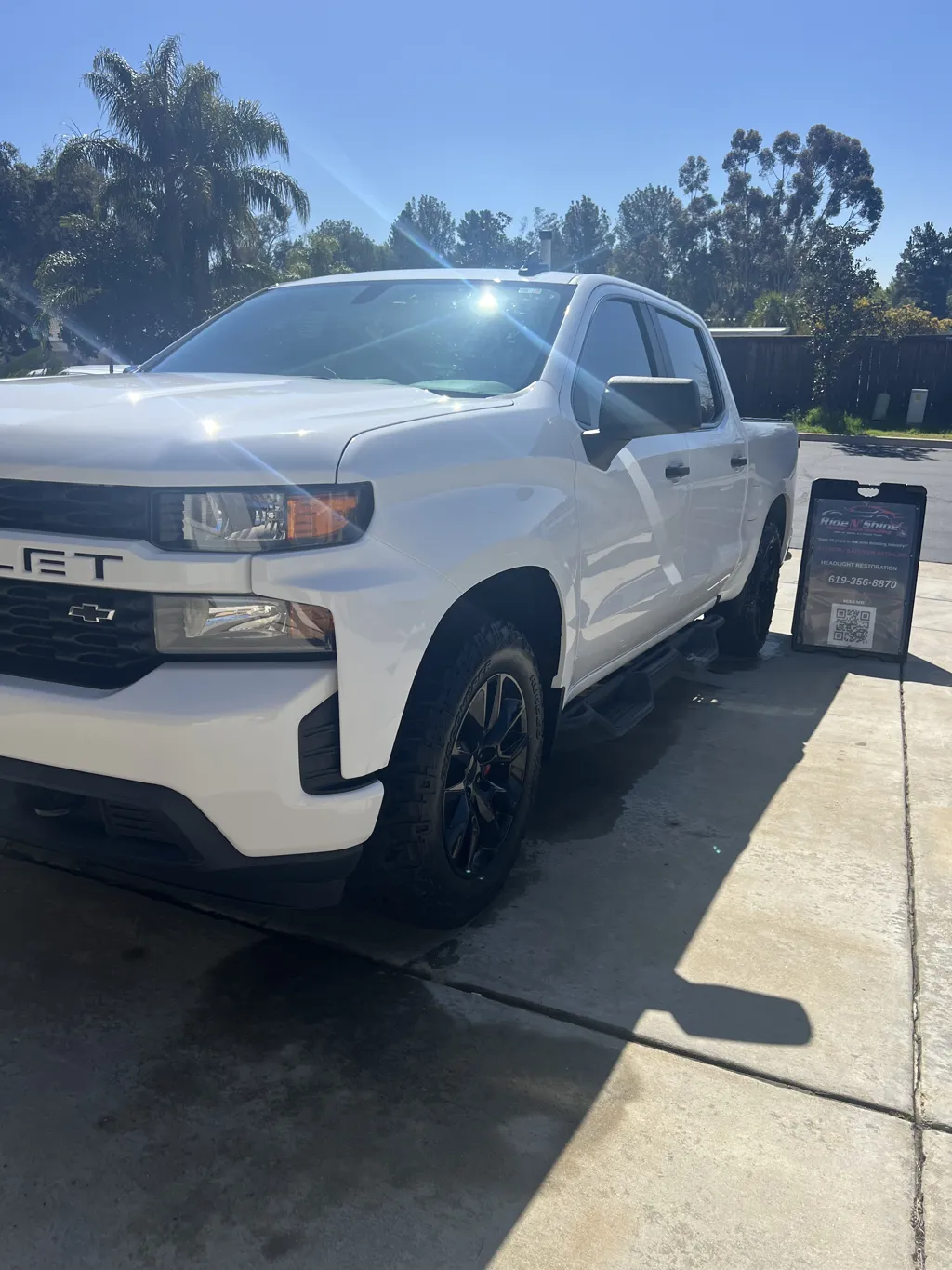 Freshly detailed white Chevrolet truck next to a Ride N Shine sign in La Mesa CA